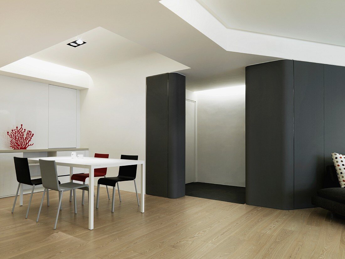 Moderne Tischgarnitur und eine schwarze, leicht abgerundete Wand im futuristisch angehauchten Esszimmer