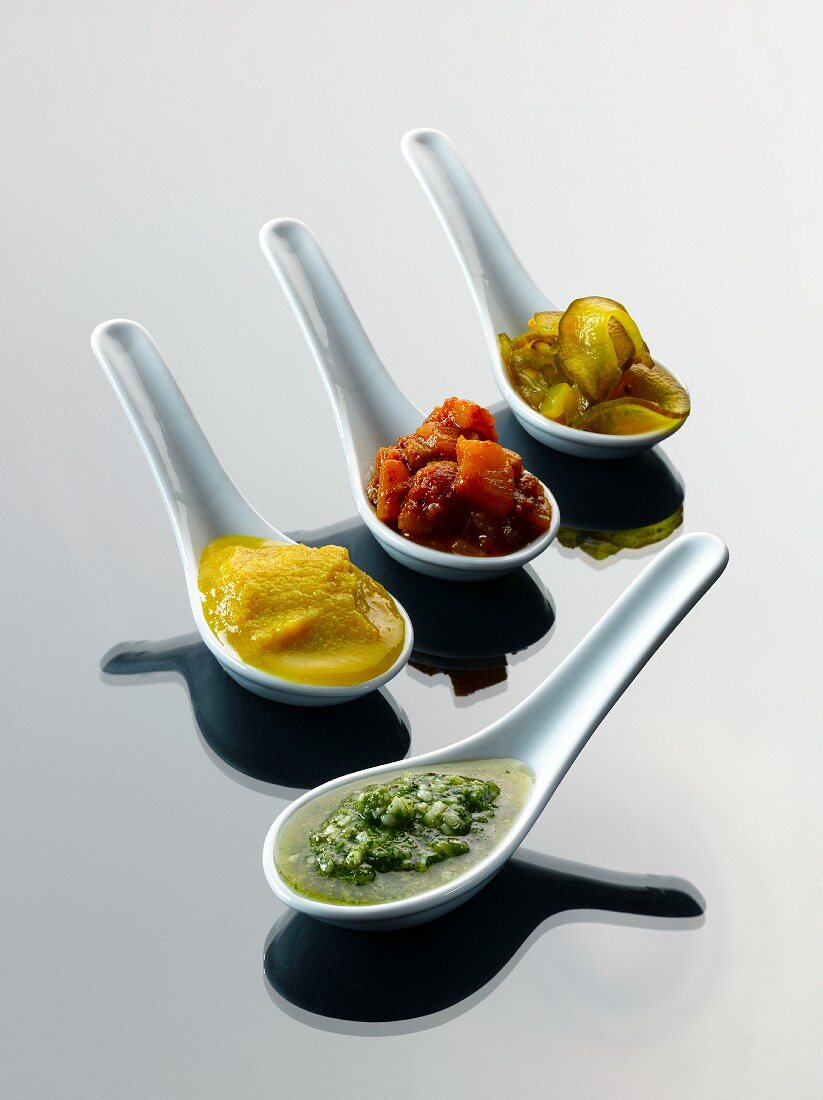 Pest, piccalilli, pear chutney and cucumber relish on tasting spoons
