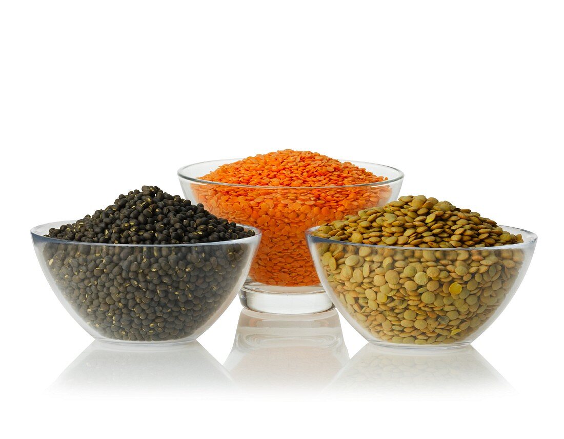 Urid beans, red lentils and green lentils in glass bowls