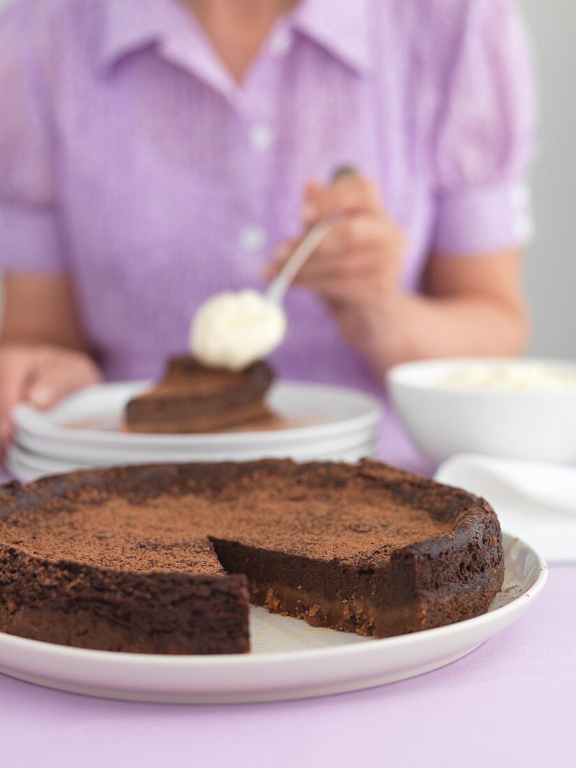 A woman eating a chocolate cake with cream