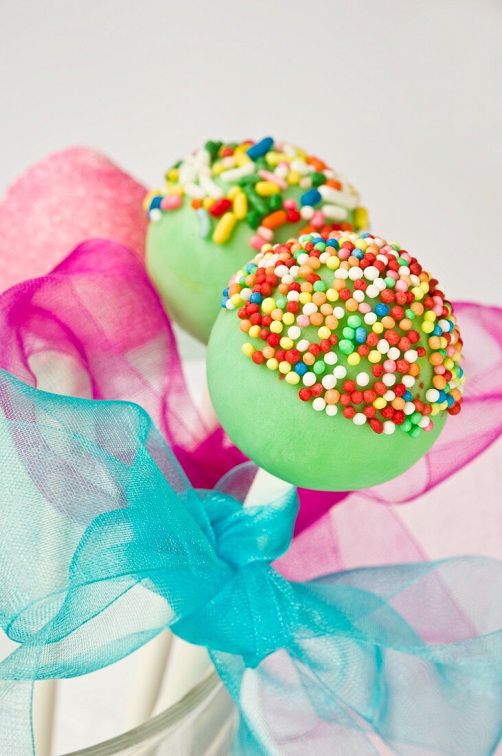 Cake pops decorated with colourful sugar sprinkles and bows