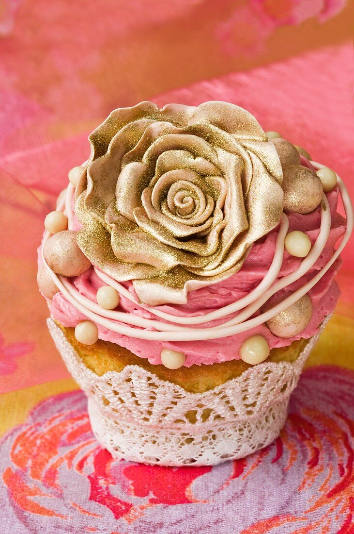 A cupcake decorated with a gold rose and buttercream