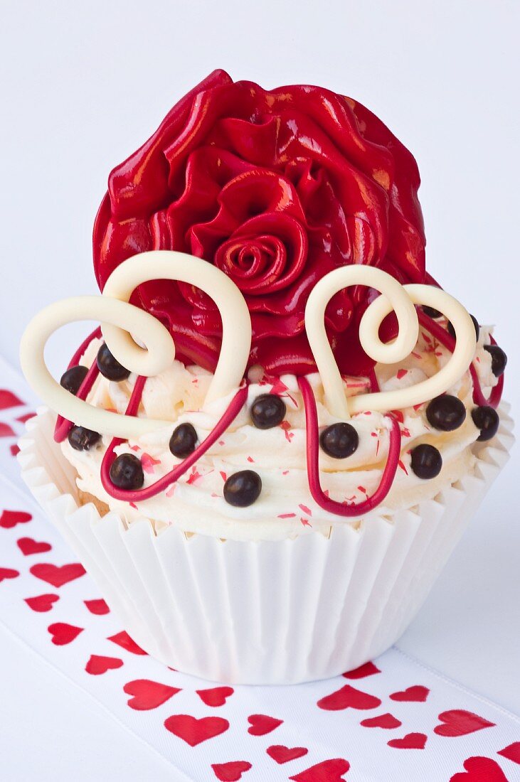 A cupcake decorated with hearts and a red rose for Valentine's Day