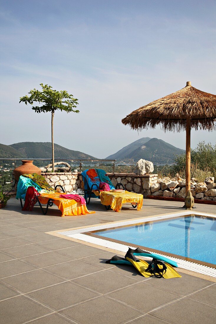 Ruheliegen mit bunten Badetüchern am Swimmingpool auf der Terrasse (Villa Octavius, Lefkas, Griechenland)