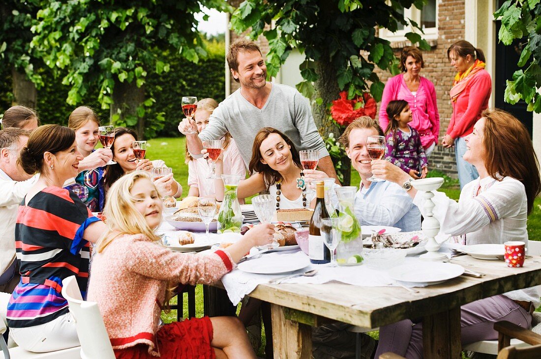 Menschen beim Anstoßen auf einer Gartenparty