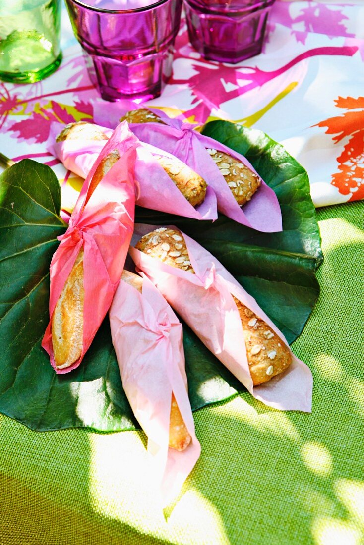 Bread rolls, wrapped in colourful paper napkins, at a summer buffet