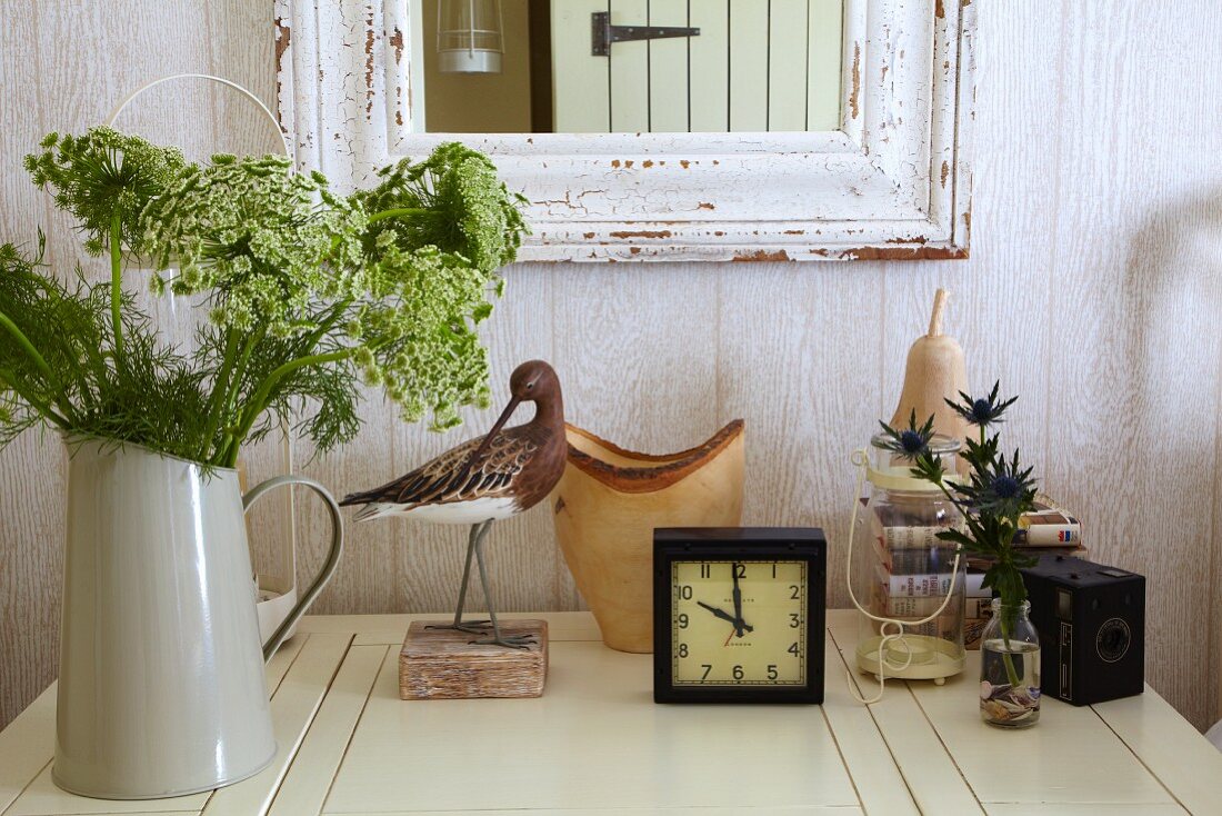 Flowers, alarm clock and ornaments on white table