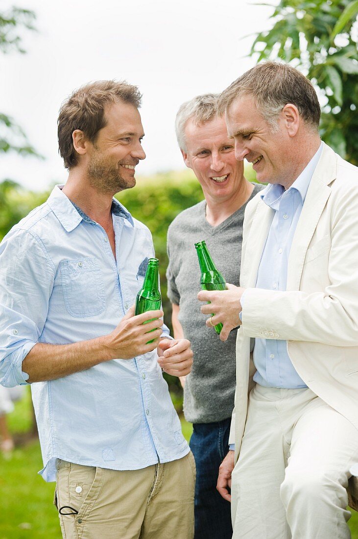 Three men with bottles of beer outdoors
