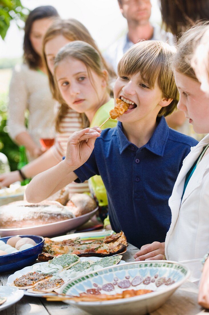 Children standing by a buffet at a garden party