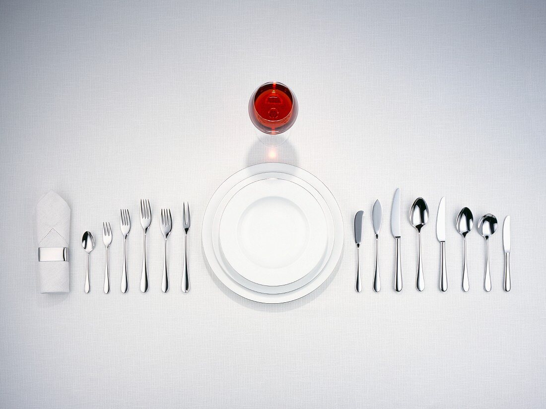 Plates, cutlery, a napkin and a glass of red wine