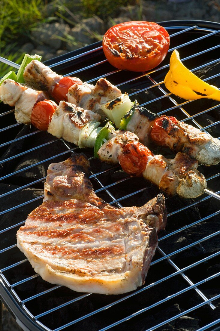 Grillspiesse und Schweinekotelett mit Grillgemüse auf dem Holzkohlegrill