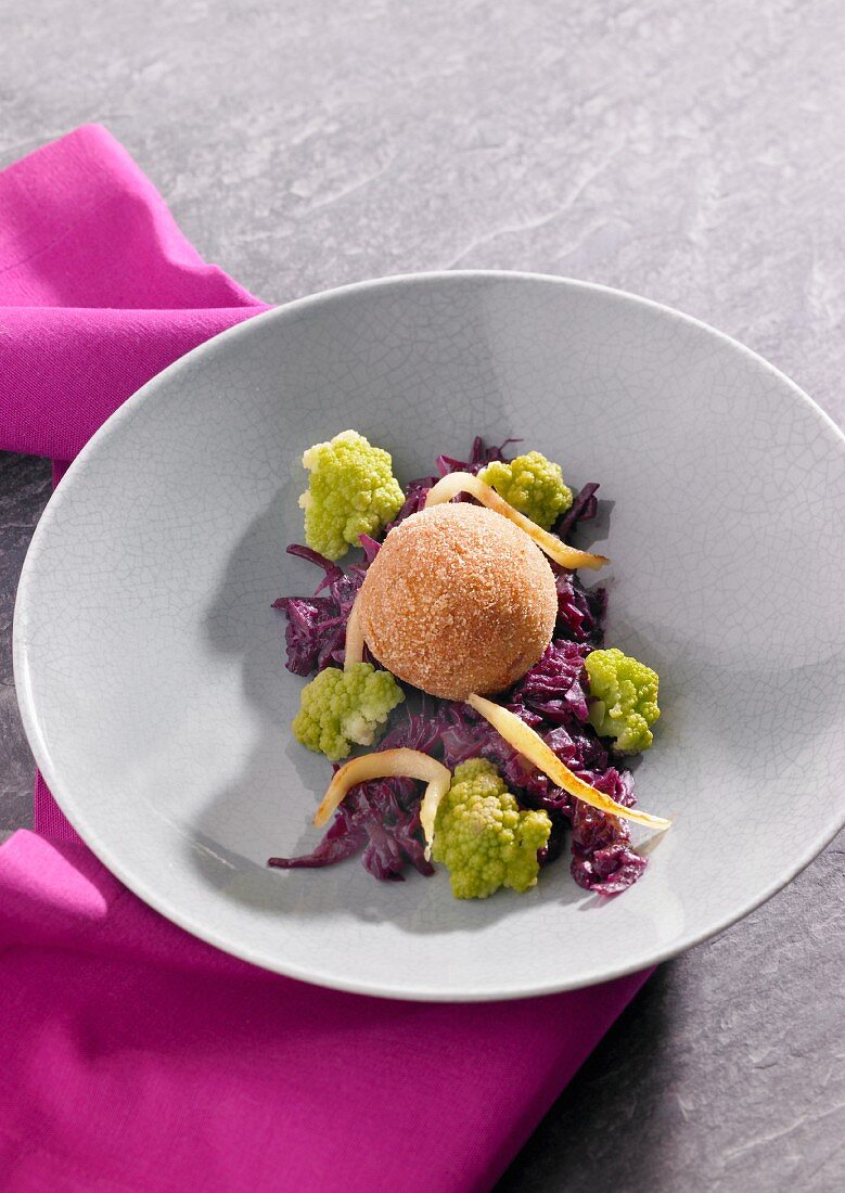 A dumpling on a bed of red cabbage and cauliflower