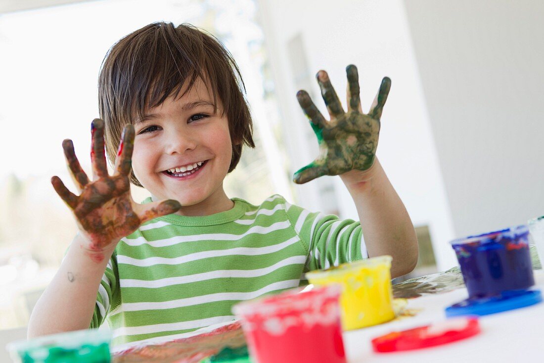 Smiling boy finger painting indoors