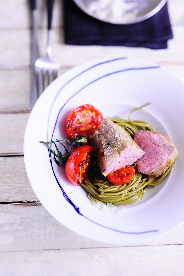 Veal fillet on a bed of noodle with tomatoes