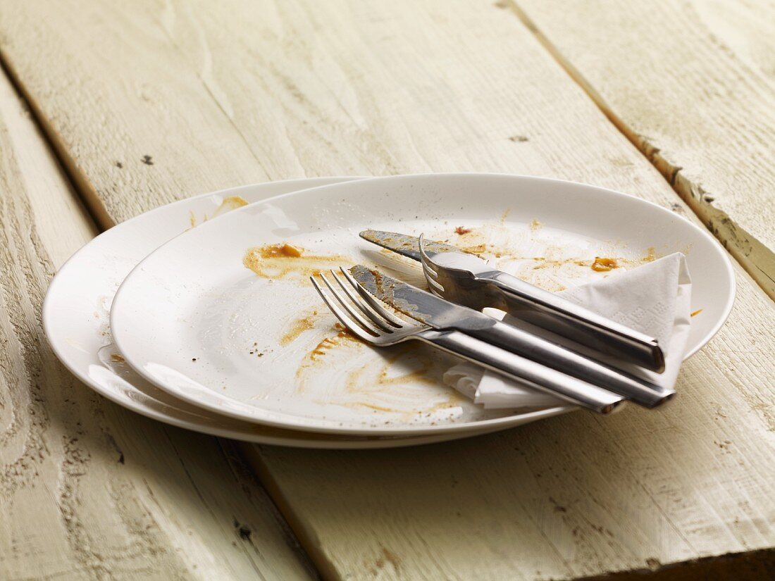 A dirty plate with cutlery and a paper napkin