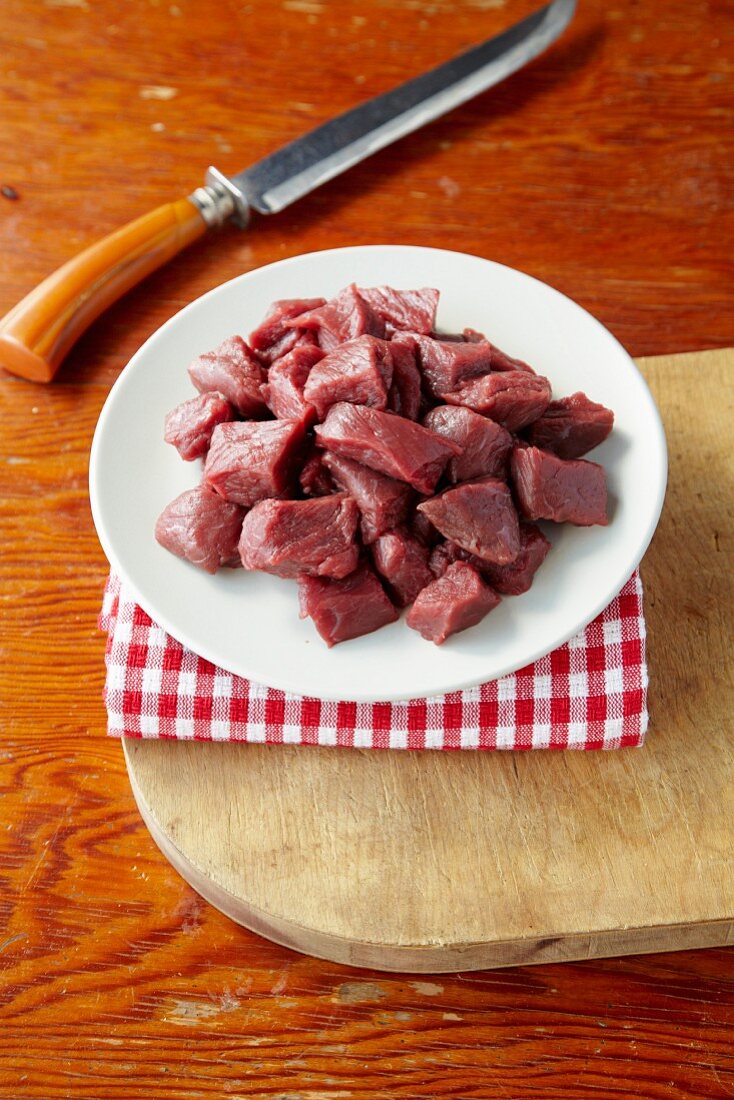 Chunks of Buffalo Stew Meat on a Plate; Butcher Knife