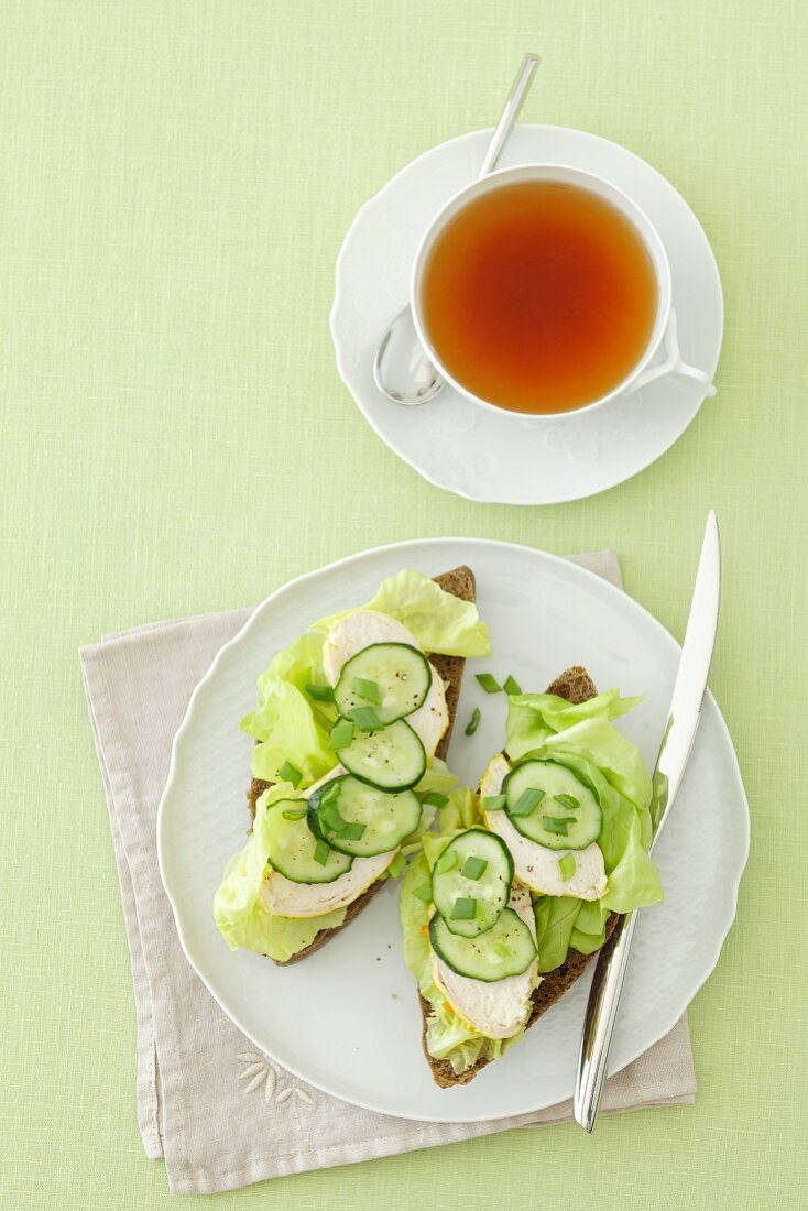 Wholemeal bread topped with chicken breast, lettuce and cucumber with a cup of tea