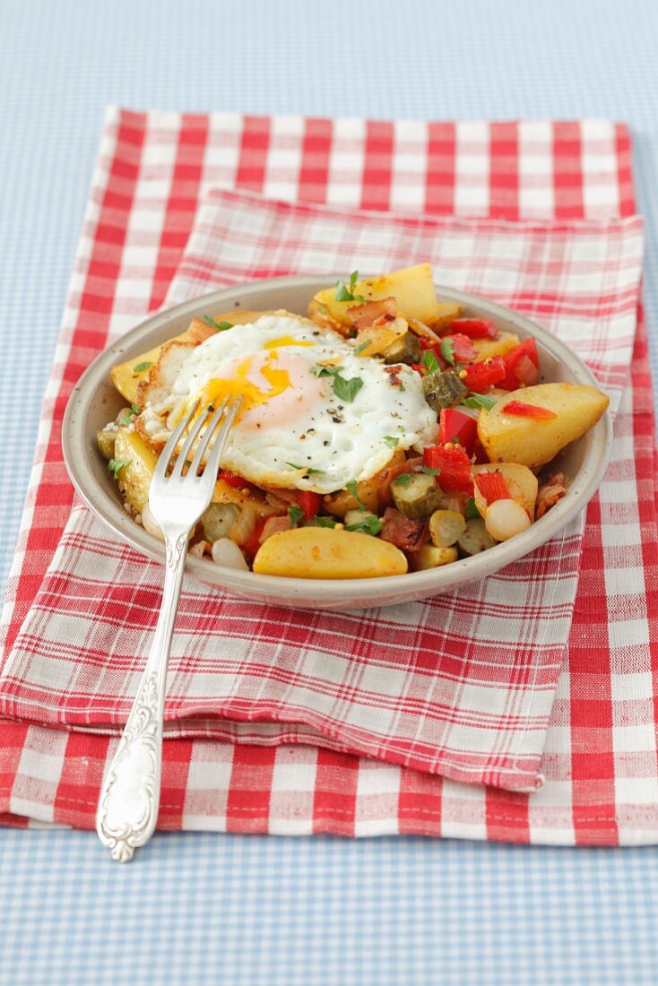 Fried potatoes with pancetta, peppers, gherkins and a fried egg