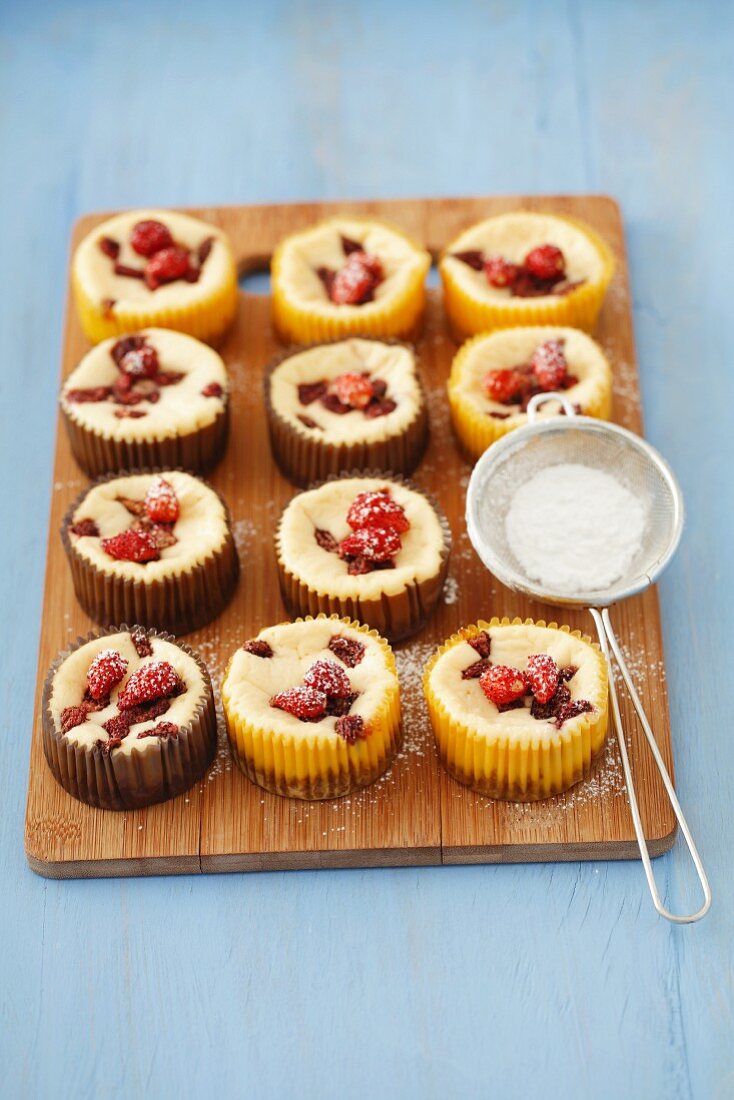 Mini cheesecakes with wild strawberries and icing sugar