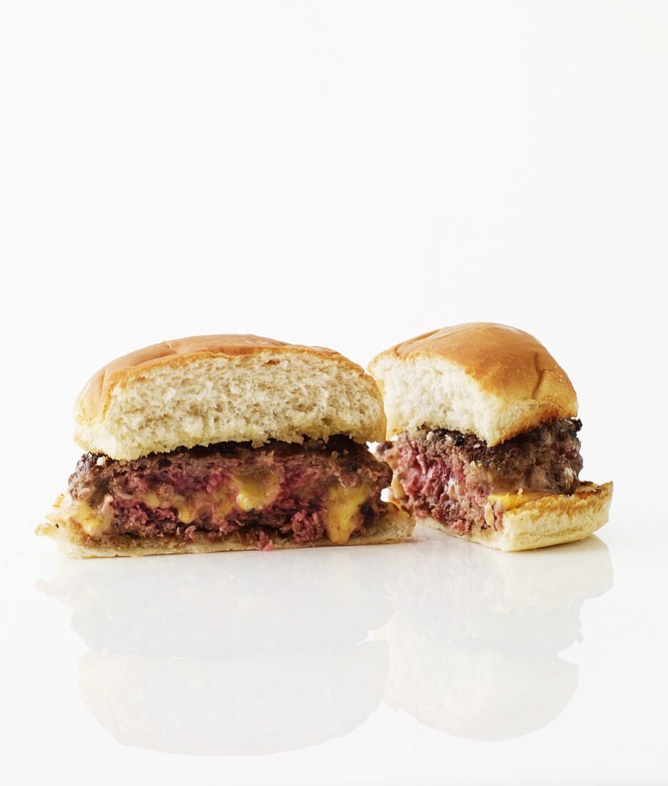 Halbierter Hamburger mit Käsefüllung vor weißem Hintergrund