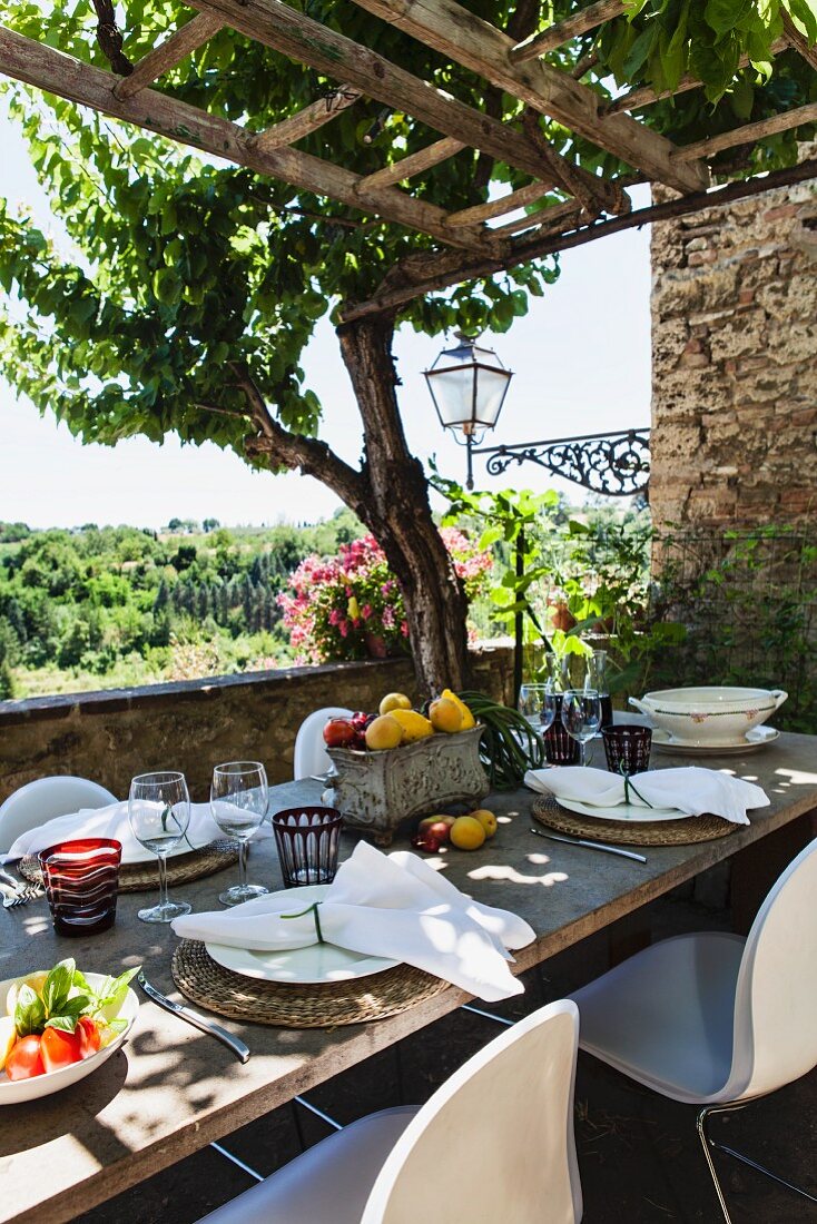 Gedeckter Tisch auf rustikaler Terrasse mit Pergola