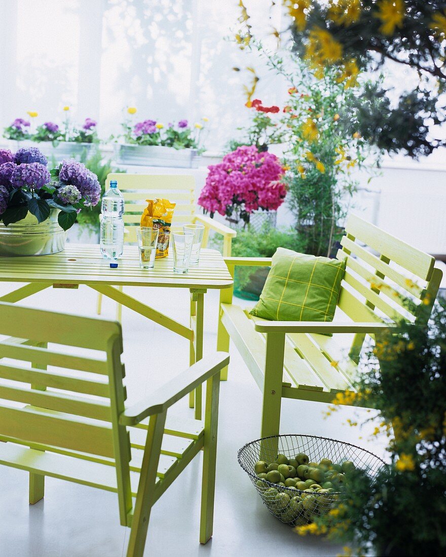 Summer mood in a conservatory - modern patio furniture in green and flower pots with assorted flowers
