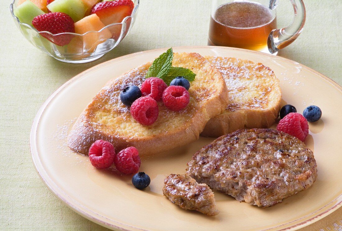 Geflügelwurstfrikadelle und French Toast mit frischen Beeren, Ahornsirup, Obstsalat