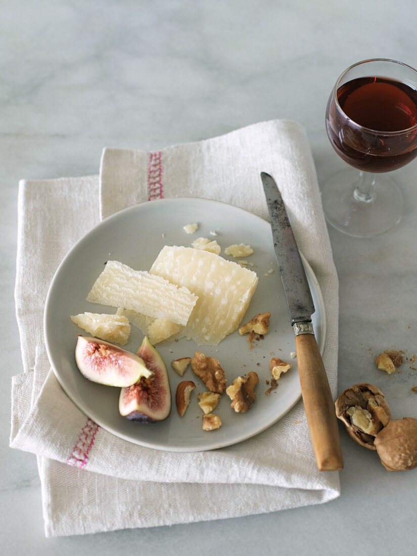 Parmesan, Feigen und Walnüsse auf einem Teller, Rotweinglas