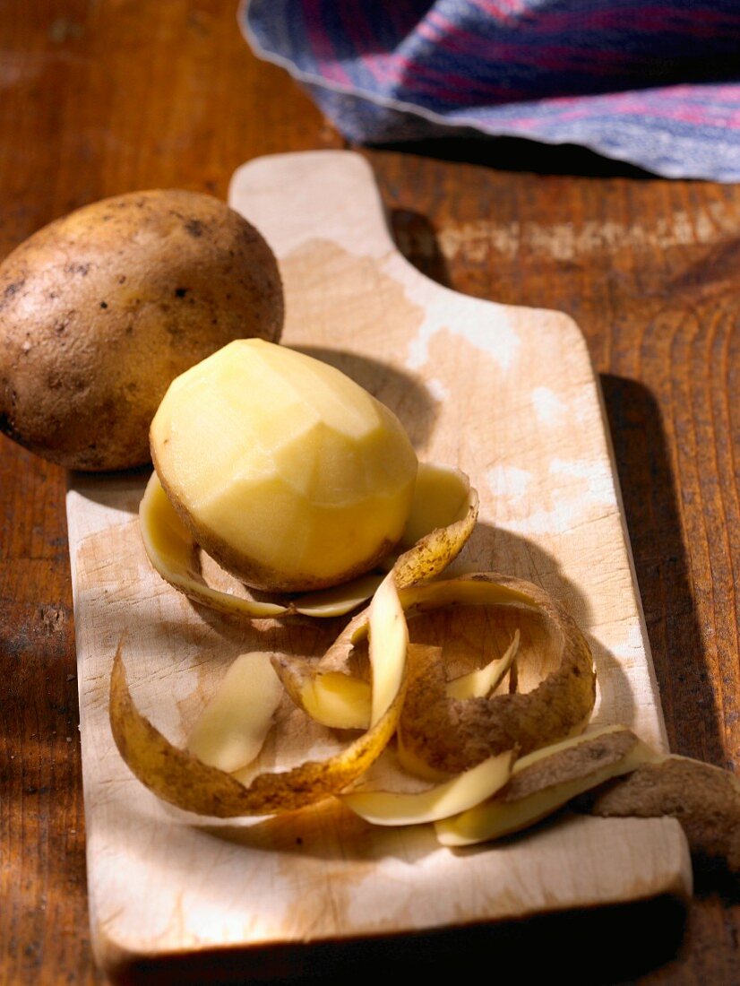 Kartoffeln, ganz & geschält auf Holzbrett