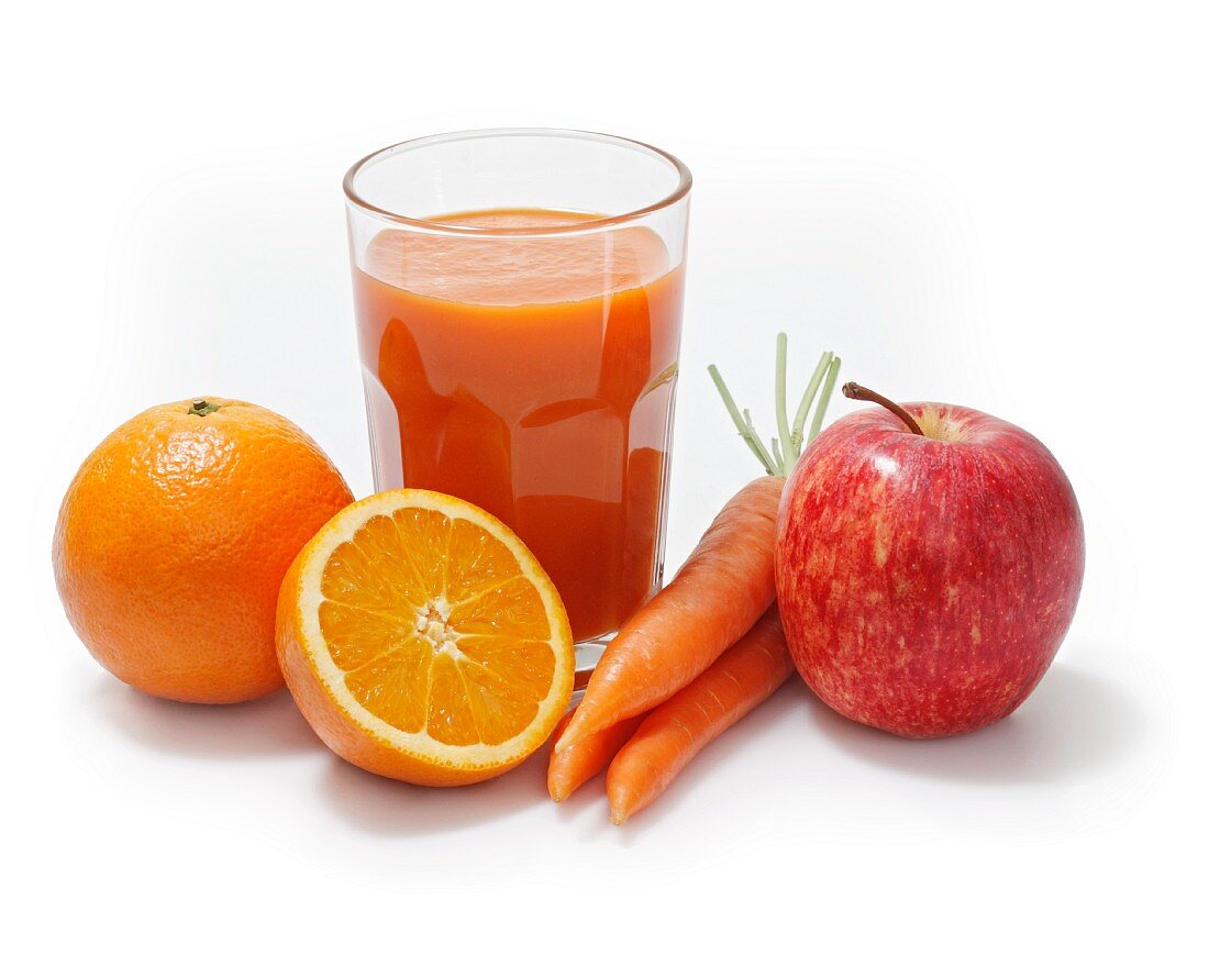 Multivitaminsaft umgeben von Orangen, Äpfeln und Karotten