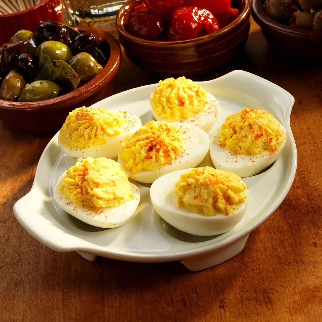 Dish of Deviled Eggs with Olives and Peppers in the Background