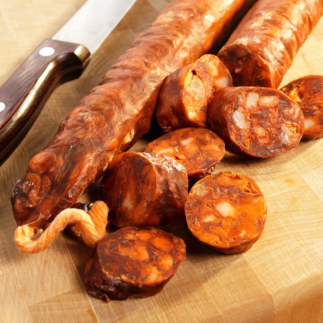 Chorizo, ganz & in Scheiben geschnitten auf Holzschneidebrett