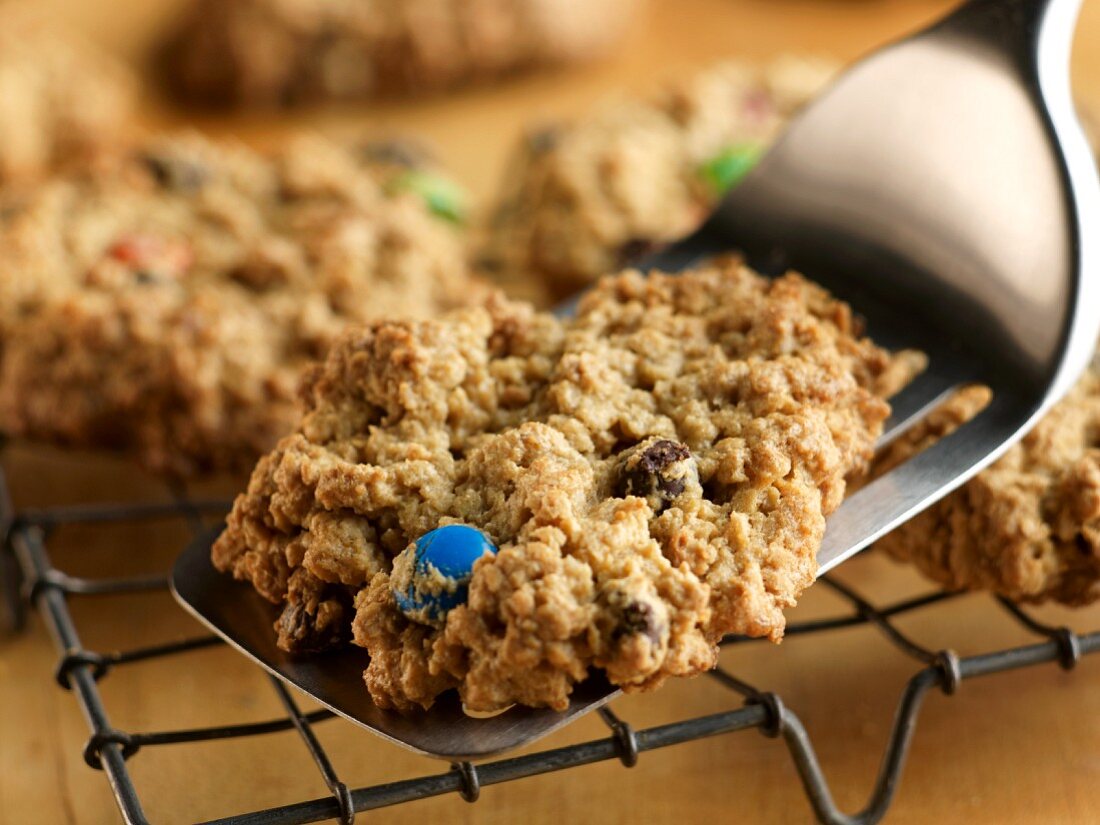 Cookies mit Schokolinsen auf Kuchengitter legen