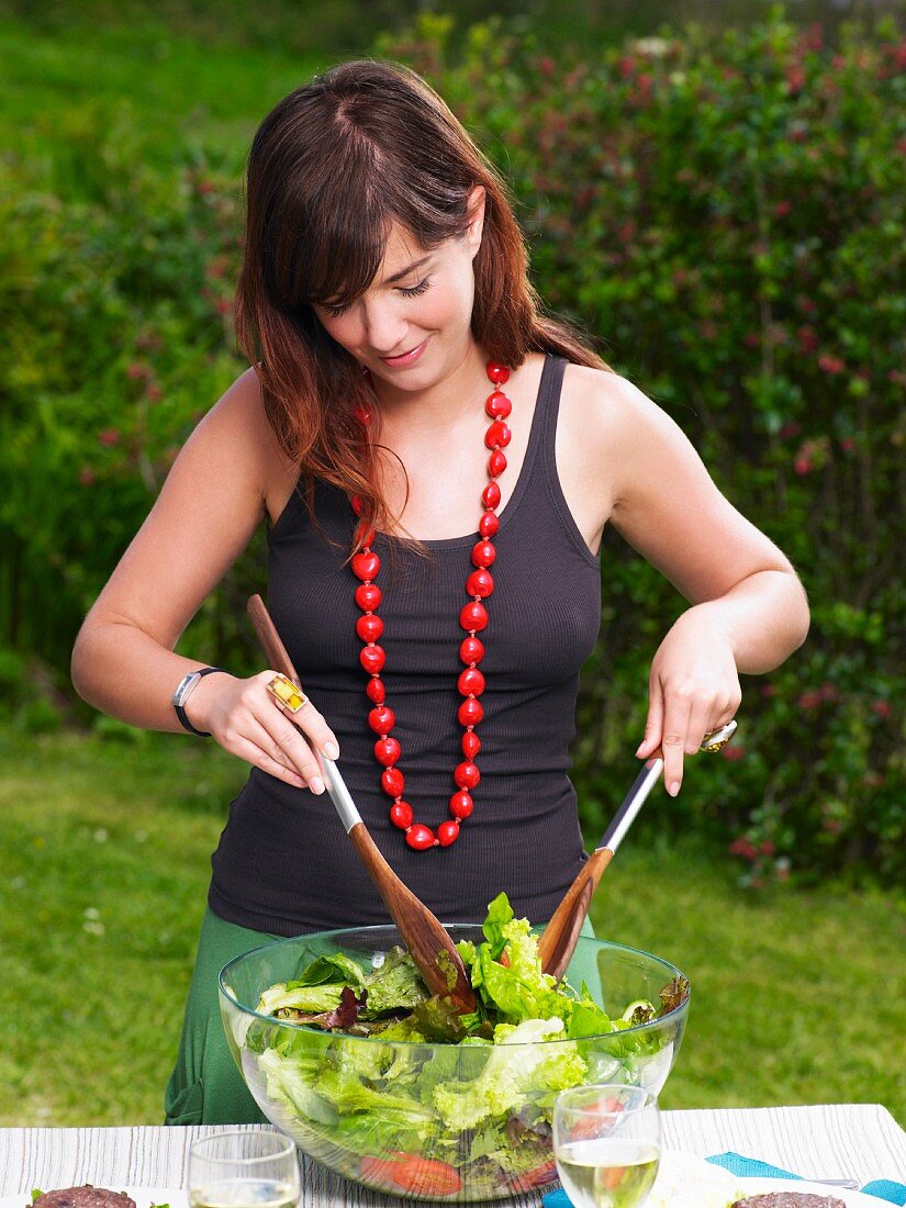 Junge Frau vermischt Salat in einer Schüssel