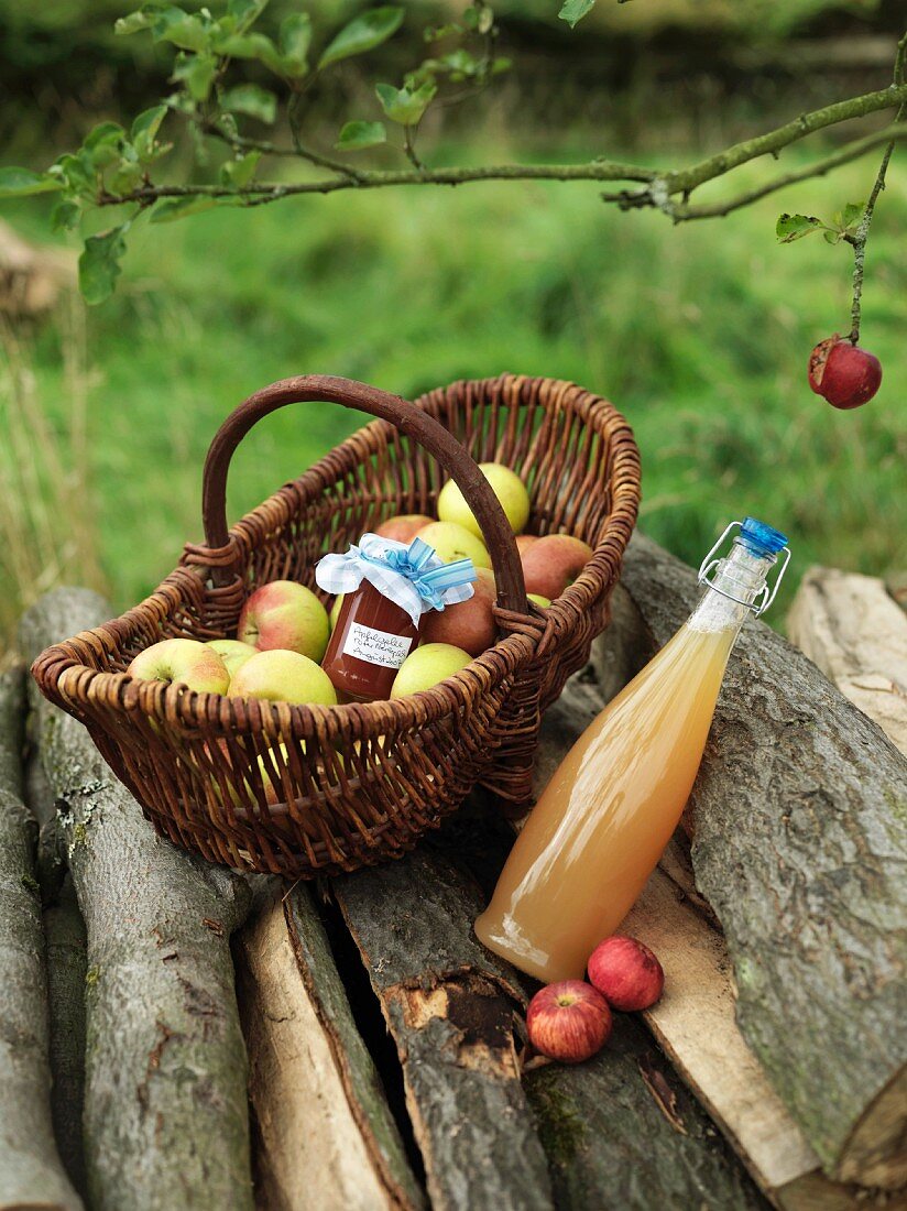 Äpfel im Korb mit Marmeladenglas und Saft