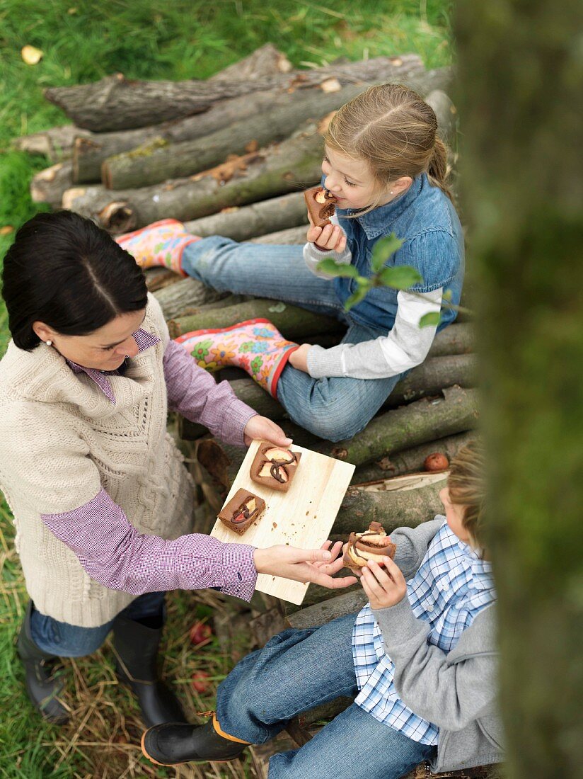 Frau und Kinder essen Apfelkuchen im Garten