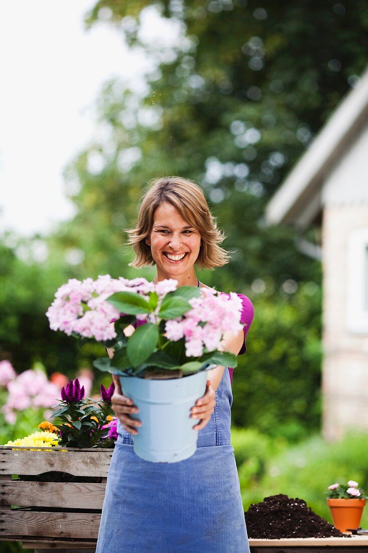 Frau zeigt einen Eimer mit Blumen