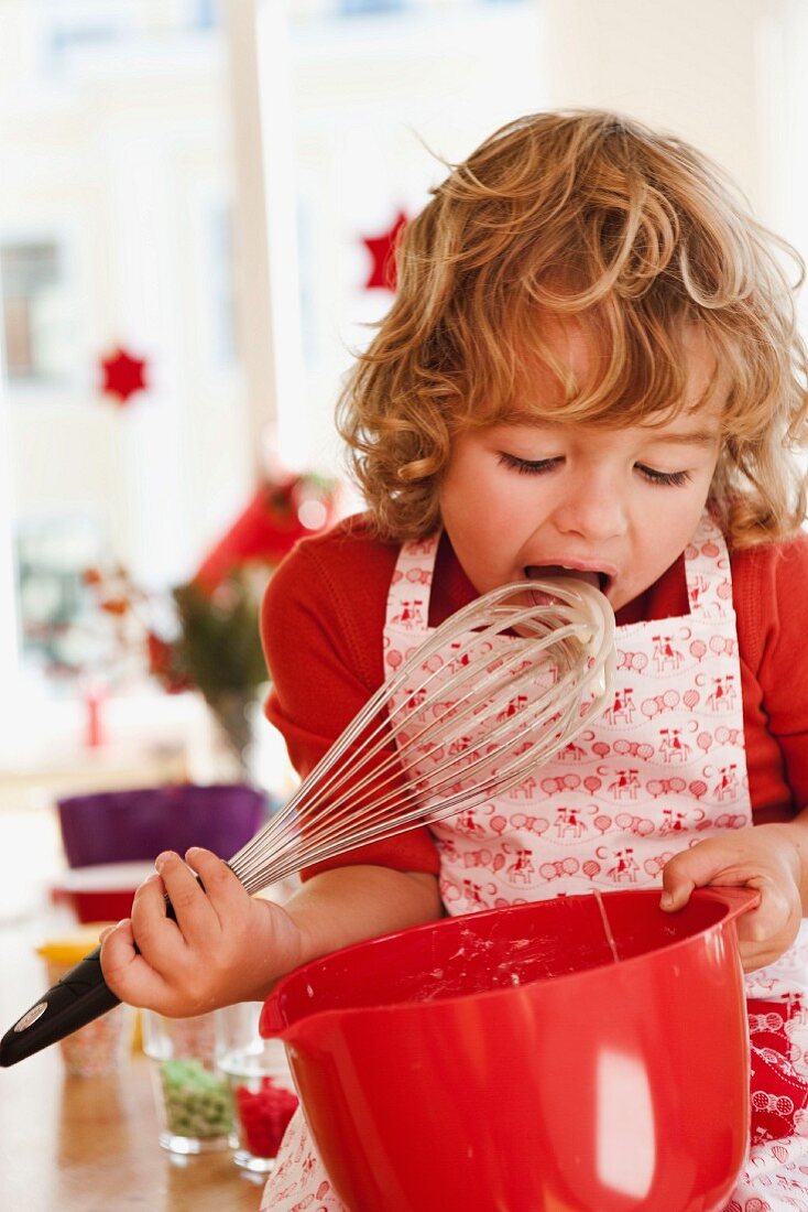 Young boy licking dough from beater