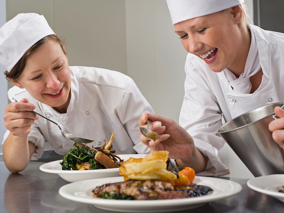 Two female chefs finish some dinners