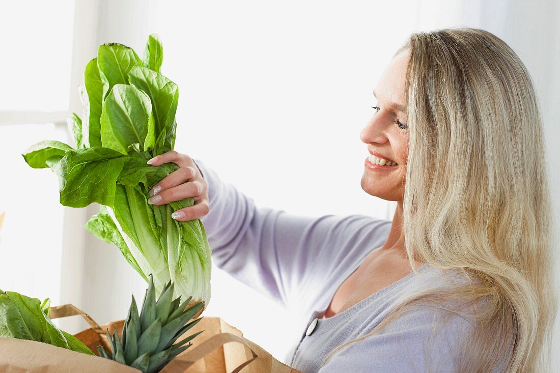 Frau packt Salat aus Einkaufstüte