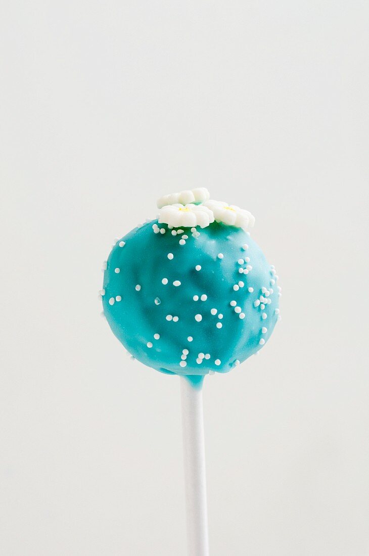 Blauer Cake Pop mit weißen Zuckerperlen und Blumen