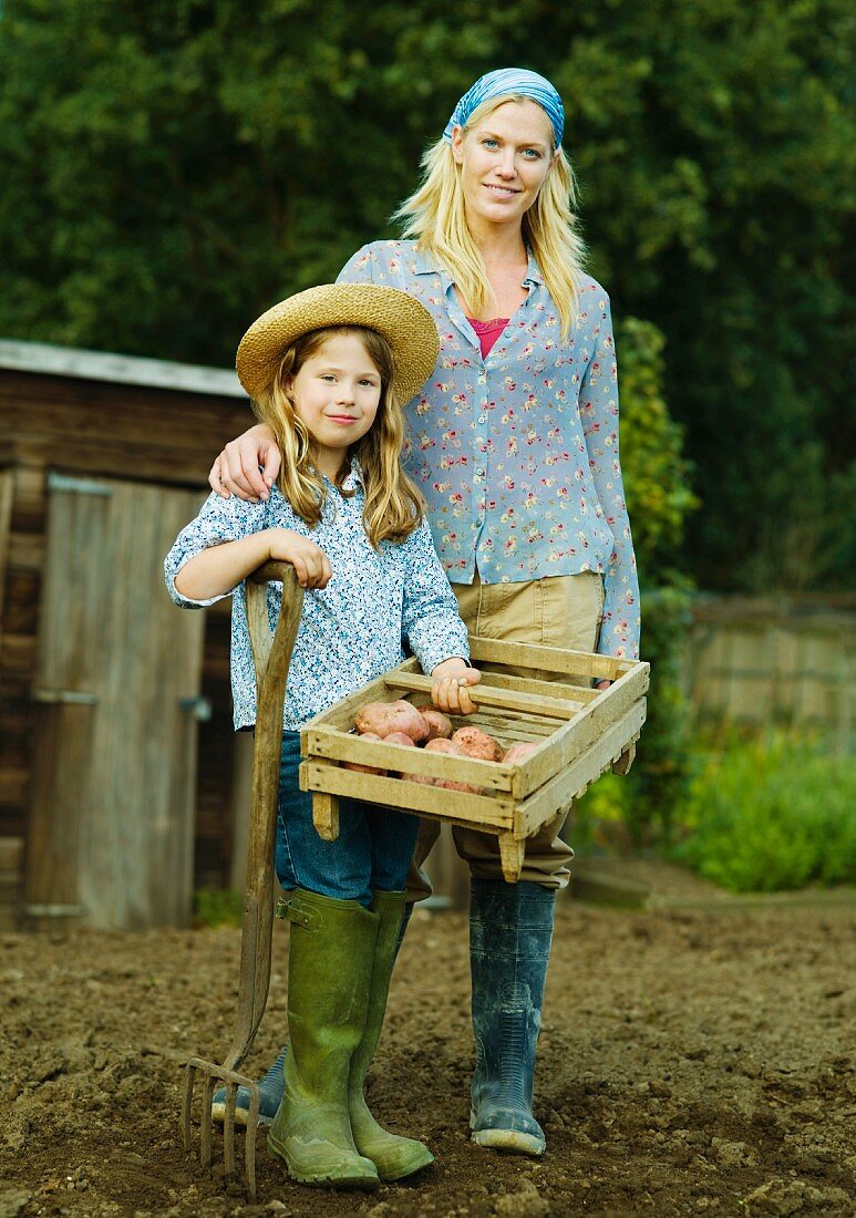 Mutter & Tochter im Garten mit Kiste frisch geernteter Kartoffeln