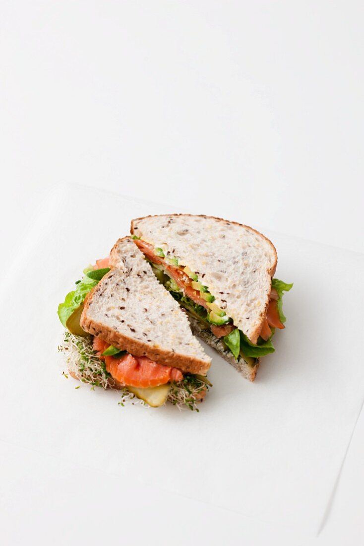 Sandwich with smoked salmon and sprouts in front of white background