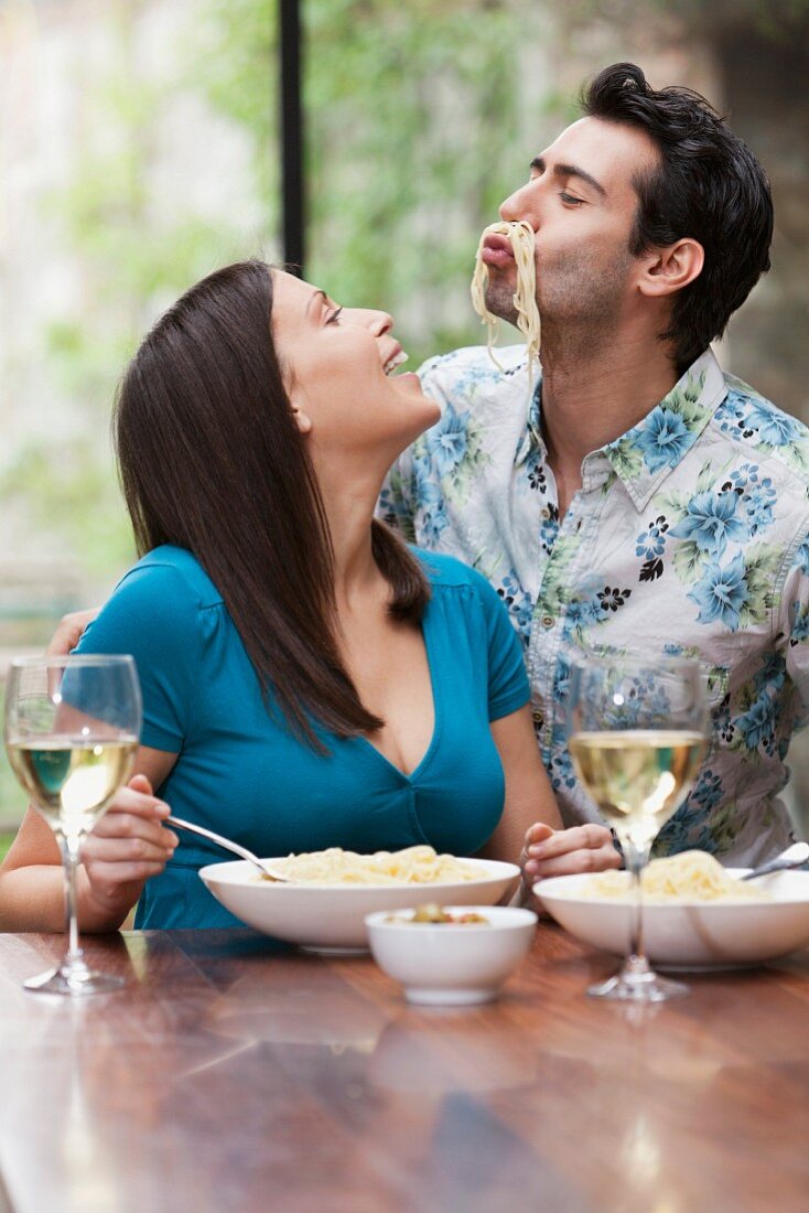 Playful couple eating together at table