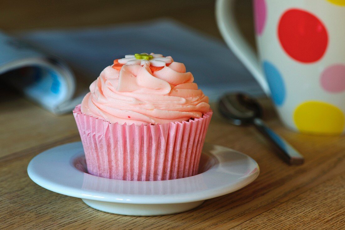 A pink cupcake decorated with sugar flowers