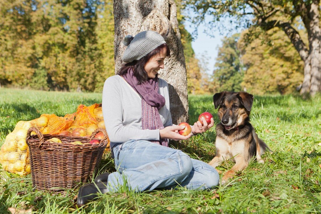 Frau mit Hund unter einem Apfelbaum