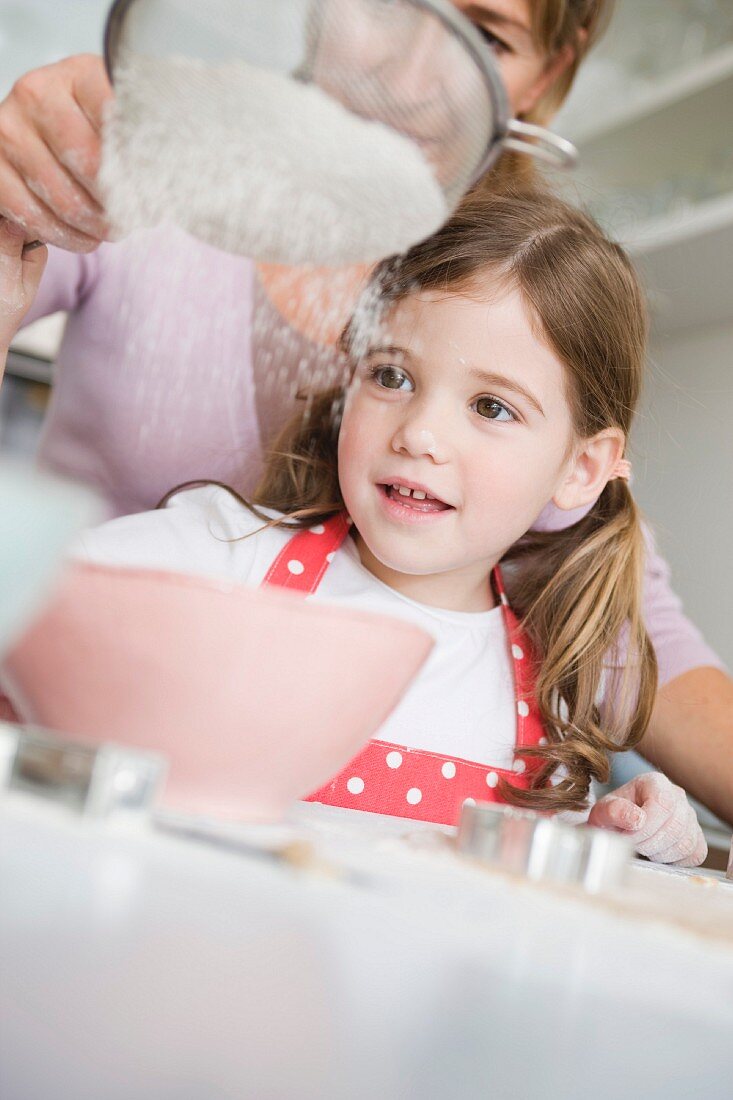 Mother and daughter sifting flour