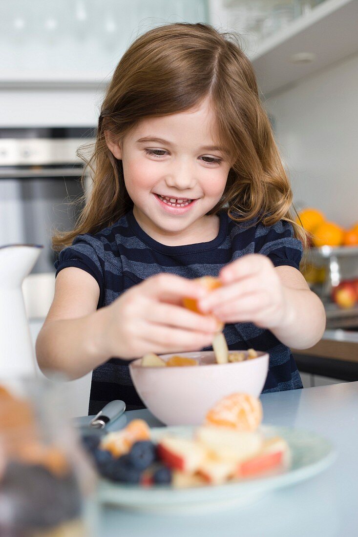 Girls putting fruit into her yogurt