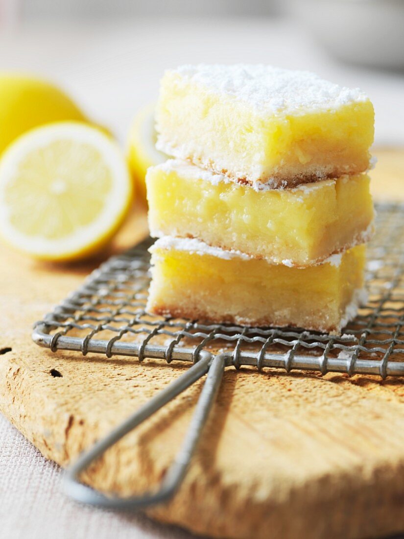 Three Lemon Bars Topped with Powdered Sugar Stacked on a Plate
