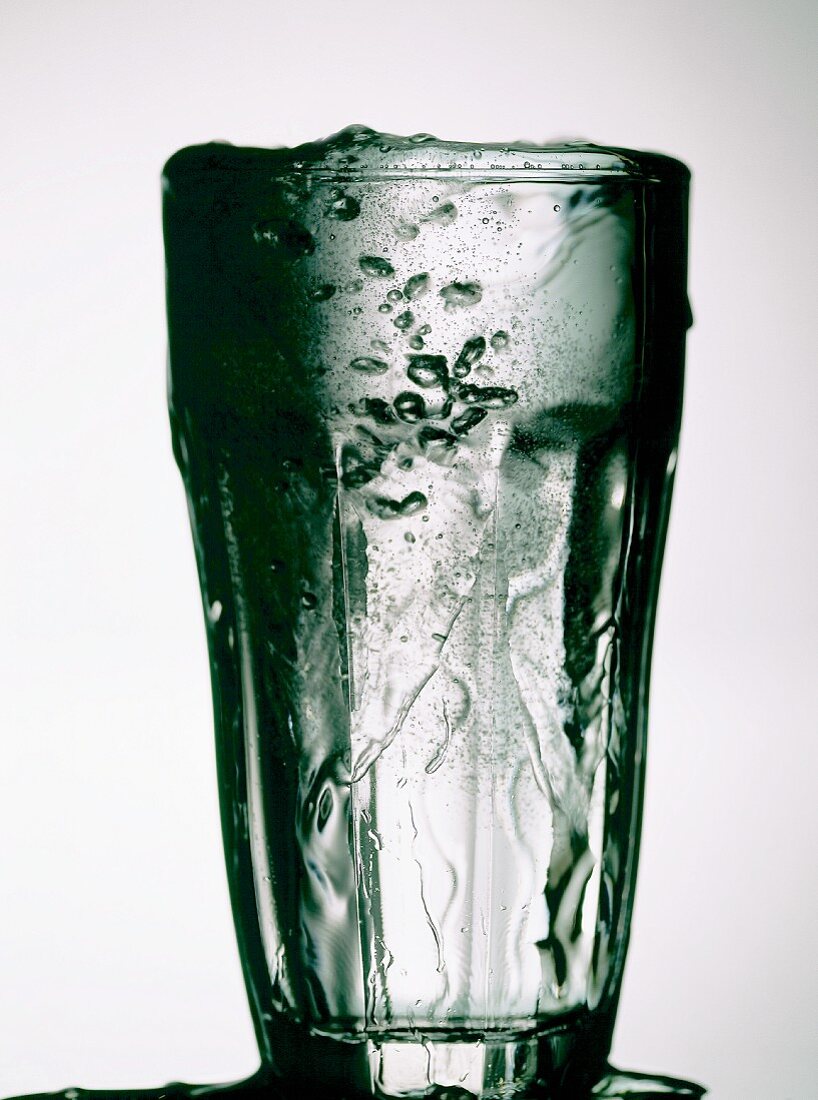 Ein Glas mit überfliessendem Wasser